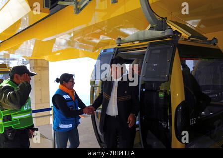 El Alto, Bolivie, 15 septembre 2014. Le président bolivien Evo Morales Ayma (au centre) descend d'une télécabine et serre la main d'un employé alors qu'il arrive à la gare de Ciudad Satelite pour la cérémonie d'inauguration de la ligne jaune. La ligne jaune est la deuxième des trois lignes de téléphériques qui seront ouvertes cette année, et fait partie d’un projet ambitieux visant à soulager les embouteillages. La première ligne a ouvert ses portes en mai, lorsque les trois seront ouvertes, ce sera le plus long réseau de téléphérique urbain du monde. Derrière lui se trouve le vice-président Alvaro Garcia Linera (cheveux blancs). Banque D'Images