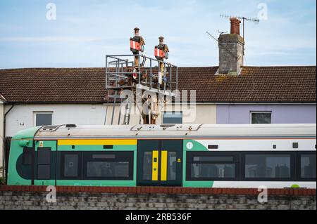 Train Electrostar de classe 377 passant devant un vieux sémaphore mécanique signal portique près de la gare de Littlehampton, Royaume-Uni, avec des maisons en arrière-plan. Banque D'Images