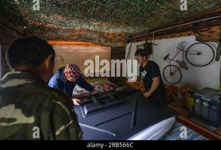 (230707) -- GONGSHAN, 7 juillet 2023 (Xinhua) -- Gan Wenyong et des travailleurs ont monté la télévision à la bibliothèque 'Banshan Huayu' dans le village de Qiunatong, dans le canton de Bingzhongluo dans le comté autonome de Gongshan Dulong et nu, préfecture autonome de Lisu de Nujiang, province du Yunnan, au sud-ouest de la Chine, 6 juillet 2023. La rivière Nujiang, descendant des montagnes Tanggula sur le plateau Qinghai-Tibet, se fraie un chemin à travers les majestueuses montagnes du Yunnan où se forme un magnifique canyon. Niché à la pointe nord du canyon de la rivière Nujiang est le village de Qiunatong, qui abrite une bibliothèque unique c Banque D'Images