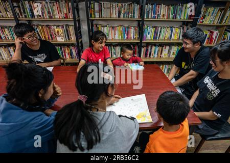 (230707) -- GONGSHAN, 7 juillet 2023 (Xinhua) -- Gan Wenyong participe à une activité de lecture avec des enfants à la bibliothèque 'Banshan Huayu' dans le village de Qiunatong, dans le canton de Bingzhongluo, dans le comté autonome de Gongshan Dulong et nu, préfecture autonome de Lisu de Nujiang, province du Yunnan, au sud-ouest de la Chine, le sud-ouest, le 5 juillet 2023. La rivière Nujiang, descendant des montagnes Tanggula sur le plateau Qinghai-Tibet, se fraie un chemin à travers les majestueuses montagnes du Yunnan où se forme un magnifique canyon. Niché à la pointe nord du canyon de la rivière Nujiang est le village de Qiunatong, qui abrite Banque D'Images