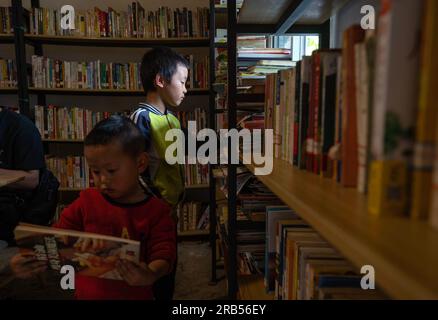 (230707) -- GONGSHAN, 7 juillet 2023 (Xinhua) -- Un enfant choisit des livres à la bibliothèque 'Banshan Huayu' dans le village de Qiunatong, dans le canton de Bingzhongluo dans le comté autonome de Gongshan Dulong et nu, préfecture autonome Lisu de Nujiang, province du Yunnan, au sud-ouest de la Chine, le 5 juillet 2023. La rivière Nujiang, descendant des montagnes Tanggula sur le plateau Qinghai-Tibet, se fraie un chemin à travers les majestueuses montagnes du Yunnan où se forme un magnifique canyon. Niché à l'extrémité nord du canyon de la rivière Nujiang se trouve le village de Qiunatong, qui abrite une bibliothèque unique appelée 'Banshan Huay Banque D'Images