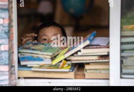 (230707) -- GONGSHAN, 7 juillet 2023 (Xinhua) -- Un enfant choisit des livres à la bibliothèque 'Banshan Huayu' dans le village de Qiunatong, dans le canton de Bingzhongluo dans le comté autonome de Gongshan Dulong et nu, préfecture autonome Lisu de Nujiang, province du Yunnan, au sud-ouest de la Chine, le 5 juillet 2023. La rivière Nujiang, descendant des montagnes Tanggula sur le plateau Qinghai-Tibet, se fraie un chemin à travers les majestueuses montagnes du Yunnan où se forme un magnifique canyon. Niché à l'extrémité nord du canyon de la rivière Nujiang se trouve le village de Qiunatong, qui abrite une bibliothèque unique appelée 'Banshan Huay Banque D'Images