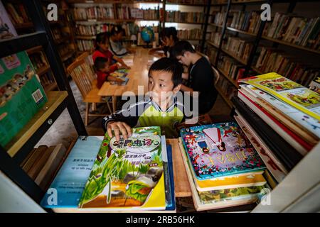 (230707) -- GONGSHAN, 7 juillet 2023 (Xinhua) -- Un enfant choisit des livres à la bibliothèque 'Banshan Huayu' dans le village de Qiunatong, dans le canton de Bingzhongluo dans le comté autonome de Gongshan Dulong et nu, préfecture autonome Lisu de Nujiang, province du Yunnan, au sud-ouest de la Chine, le 5 juillet 2023. La rivière Nujiang, descendant des montagnes Tanggula sur le plateau Qinghai-Tibet, se fraie un chemin à travers les majestueuses montagnes du Yunnan où se forme un magnifique canyon. Niché à l'extrémité nord du canyon de la rivière Nujiang se trouve le village de Qiunatong, qui abrite une bibliothèque unique appelée 'Banshan Huay Banque D'Images