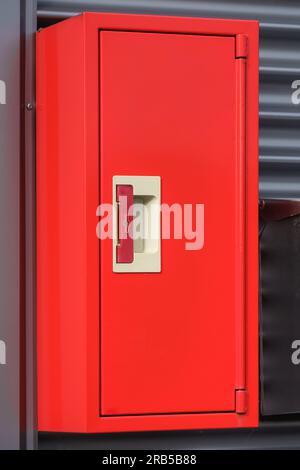 Boîte d'extincteur rouge sur un mur métallique. Banque D'Images