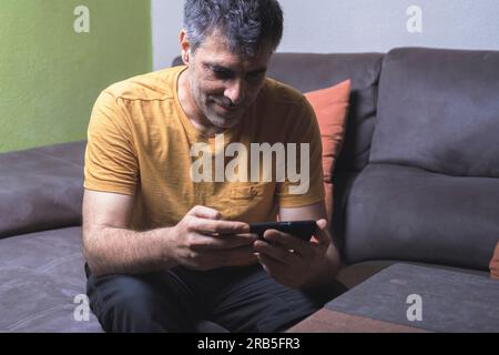 Moment de détente. Un homme profitant du confort du canapé tout en utilisant son téléphone portable. Transmet le confort et la technologie en harmonie. Banque D'Images