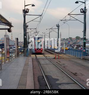 Tram allant à Kabatas se trouve à la station Karakoy un soir d'été sur le pont de Galata plein de trafic, y compris les taxis jaunes. Istanbul, Tur Banque D'Images