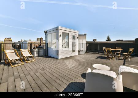 une terrasse avec deux chaises et une table sur le côté gauche de la terrasse, il y a un ciel bleu en arrière-plan Banque D'Images