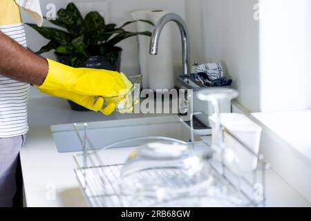 Section médiane de l'homme biracial faisant la vaisselle dans l'évier de cuisine. Mode de vie sain, corvées, nettoyage et vie domestique, inchangés. Banque D'Images