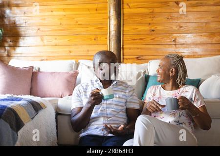 Heureux couple afro-américain senior assis sur le sol et buvant du café à la maison. Style de vie senior, détente et retraite, inchangé. Banque D'Images