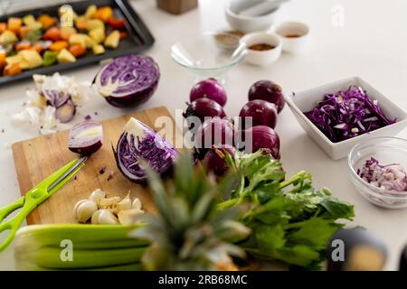 Légumes sur la planche à découper et légumes hachés dans la plaque de cuisson sur le plan de travail dans la cuisine ensoleillée. Cuisine, nourriture, ingrédients, vie saine et domesti Banque D'Images