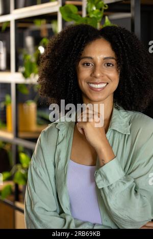 Portrait d'heureuse femme d'affaires occasionnelle biracial avec les cheveux noirs bouclés souriant dans le bureau. Travail, affaires, confiance, bien-être et bureau décontracté, unalt Banque D'Images
