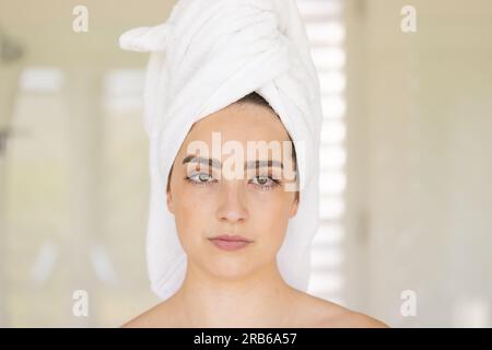 Portrait de femme caucasienne avec serviette sur la tête dans la salle de bain. Vie domestique, soins personnels et mode de vie, inchangés. Banque D'Images