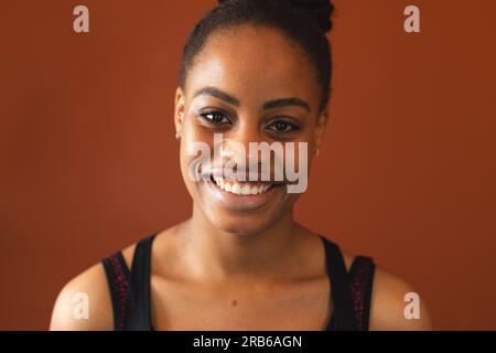 Portrait de femme afro-américaine heureuse contre le mur rouge dans le studio de yoga. Yoga, exercice, fitness et mode de vie sain, inchangés. Banque D'Images