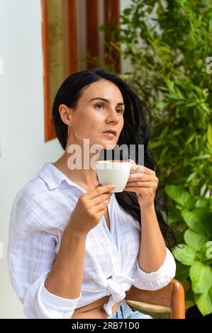 Portrait d'une femme ukrainienne souriante buvant un capuccino chaud et regardant l'appareil photo Banque D'Images