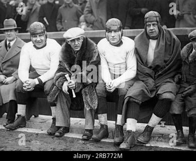 Chicago, Illinois : 23 novembre 1925 Rookie Red Grange assis sur le banc des Bears de Chicago quelques heures après avoir terminé sa spectaculaire carrière de footballeur à l'Université de l'Illinois et signé un contrat avec l'équipe professionnelle des Bears de Chicago. Il fera ses débuts le jeudi 27 novembre. De gauche à droite sont les joueurs de Bears : Ralph Scott, 'Harold 'Red' Grange, Vernon Mullen et Oscar Knop. Banque D'Images