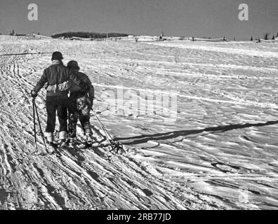 St. Sauveur, Québec, Canada : c. 1952. Un couple fatigué et heureux tête à la maison bras dans bras après une journée de ski. Banque D'Images