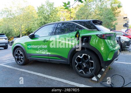 La voiture d'Enterprise CarClub en vert est connectée à la borne de recharge électrique installée dans le parking public, Greenwich Angleterre Royaume-Uni Banque D'Images