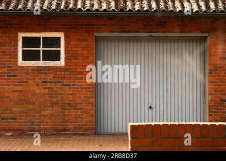 Vieilles portes de garage. Vieilles portes de garage fermées dans le mur de briques rouges. Banque D'Images