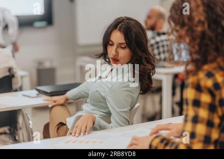 Étudiante trichant pendant l'examen, elle jette un coup d'oeil à son collègue test derrière elle Banque D'Images