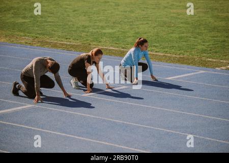 Un athlète masculin et deux athlètes féminins se préparent au sprint Banque D'Images