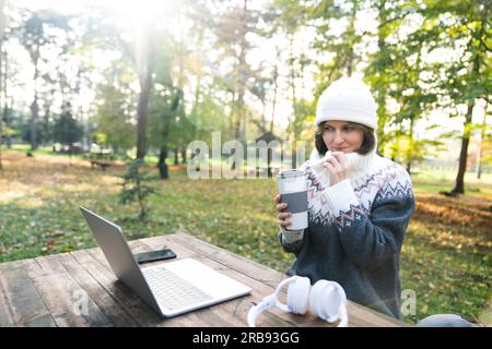 Travailleur indépendant travaillant sur ordinateur portable dans le parc d'automne. Banque D'Images