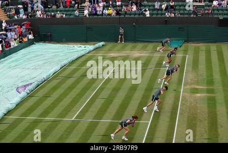 Londres, Grande-Bretagne. 8 juillet 2023. Le personnel au sol tire la housse de protection contre la pluie pour protéger le court de gazon de la pluie lors des championnats de tennis de Wimbledon à Londres, en Grande-Bretagne, le 8 juillet 2023. Crédit : Han Yan/Xinhua/Alamy Live News Banque D'Images