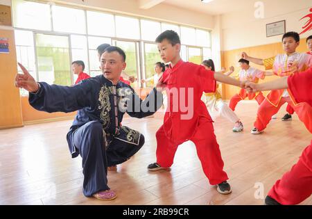 Linyi, province chinoise du Shandong. 8 juillet 2023. Un professeur d'art martial enseigne à des élèves dans le district de Lanshan de Linyi, dans la province du Shandong, dans l'est de la Chine, le 8 juillet 2023. Les étudiants de tout le pays profitent d'une variété d'activités pendant les vacances d'été. Crédit : Xu Chuanbao/Xinhua/Alamy Live News Banque D'Images