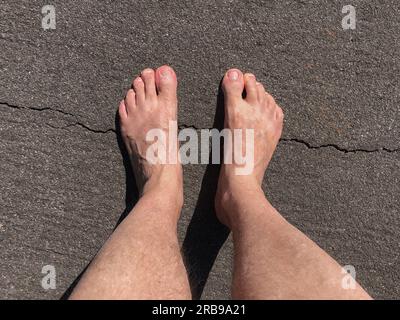 Pieds dans des sandales en caoutchouc marchant sur l'herbe et le sol de terre. Chinelo Havaianas Banque D'Images