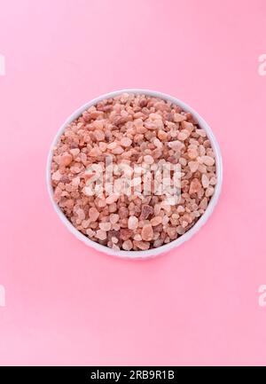 Flatly Pink Himalayan Rock Salt, halite dans un bol en céramique blanche sur fond rose. Plan vertical de la vue de dessus, Copier l'espace pour le texte. Photo de haute qualité Banque D'Images