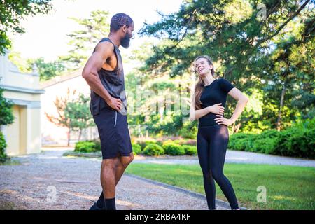 Deux coureurs ont une conversation lors d'un entraînement en plein air, amitié multi-ethnique Banque D'Images