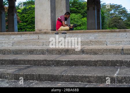Colombo, Sri Lanka -- 6 avril 2030. Photo d'un homme assis dehors et lisant un livre à Independence Memorial Hall. Banque D'Images