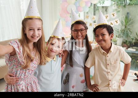 Joyeuse fille preteen prenant selfie avec des amis à la fête d'anniversaire Banque D'Images