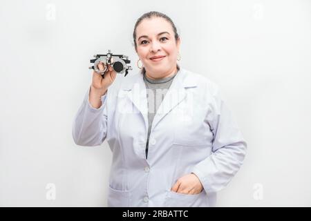 Portrait d'une optométriste tenant une lentille de Messbrille isolée. Ophtalmologiste souriant tenant une messbrille isolée Banque D'Images