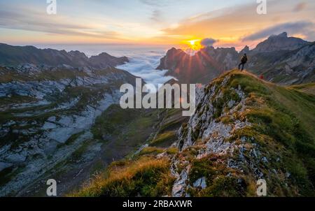 Alpiniste au lever du soleil à Rotsteinpass, étoile du soleil, brouillard élevé dans la vallée, Saentis, Appenzell Ausserrhoden, Alpes Appenzell, Suisse Banque D'Images