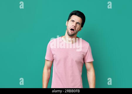 Drôle de mécontent homme dans le t-shirt rose regardant vers le haut sur fond bleu. Concept des émotions Banque D'Images