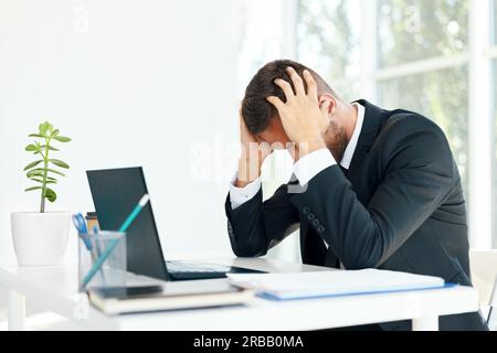 Homme d'affaires stressé et fatigué assis à la réception dans un bureau créatif. L'homme souffre de maux de tête, de problèmes concept Banque D'Images