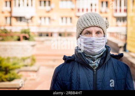 Une femme âgée pauvre porte un masque maison pour se protéger contre des virus tels que le coronavirus, également connu sous le nom de covid-19, ou le SRAS et le MERS. Elle est dans un Banque D'Images