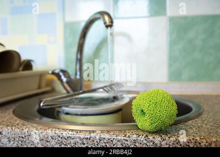 Récureur en maille de plastique vert, utilisé pour nettoyer la vaisselle, les assiettes, la casserole et les casseroles, près de l'évier dans la cuisine Banque D'Images