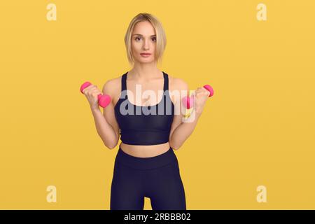 Jolie femme blonde en top d'entraînement noir avec de petits haltères roses dans ses mains, regardant la caméra. Gros plan portrait avant sur jaune ordinaire Banque D'Images