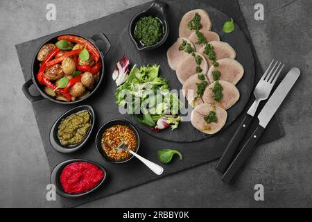 Savoureux morceaux de langue de bœuf et ingrédients servis sur une table grise, vue de dessus Banque D'Images