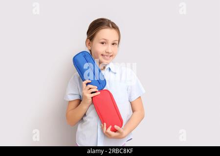 Petite fille avec des étuis à crayons sur fond clair Banque D'Images