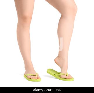 Jambes de femme en tongs sur fond blanc Banque D'Images