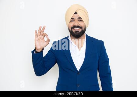 Heureux jeune homme d'affaires sikh indien portant costume Do OK geste avec la main isolée sur fond blanc. Concept d'entreprise. Banque D'Images