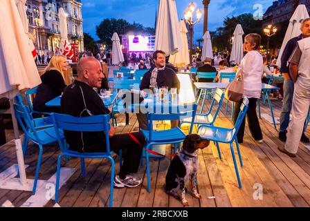 Paris, France, foule, touristes se détendant au Paris café, jour, terrasse , place de l'Hôtel de ville, regarder les Jeux Olympiques d'été à Londres, 2012, en direct sur l'écran public sur la Plaza, nuit Banque D'Images