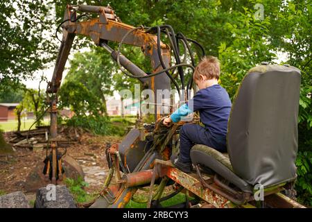 Un enfant conduit un vieux tracteur, des vacances amusantes dans le village. Banque D'Images