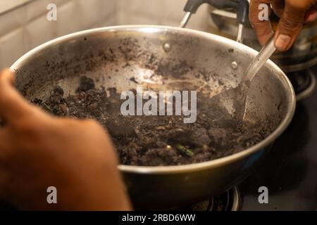 Un boucher hache de la viande de mouton et la mélange avec du sang, des épices et d'autres ingrédients. La frite est ensuite cuite dans une poêle jusqu'à ce qu'elle soit croustillante et b) Banque D'Images