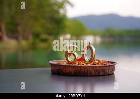 anniversaire de la personne de 60 ans avec des bougies d'or sur un gâteau dans le lac. célébration d'anniversaire d'une personne mûre Banque D'Images