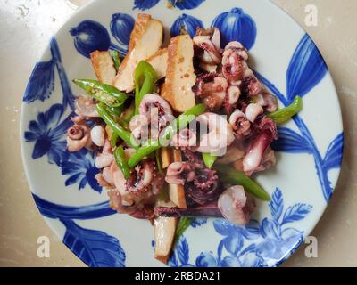 calmar frais brouillé avec du poivre et du caillé de haricots dans l'assiette bleue prêt à manger Banque D'Images