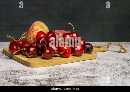 quelques délicieuses cerises mûres et quelques paraguayens sur une planche de cuisine en bambou Banque D'Images