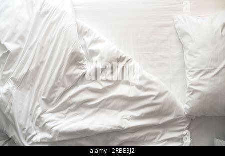 Linge de lit froissé et désordonné, linge de lit avec oreillers, drap et couverture le matin dans une chambre d'hôtel, vue de dessus Banque D'Images